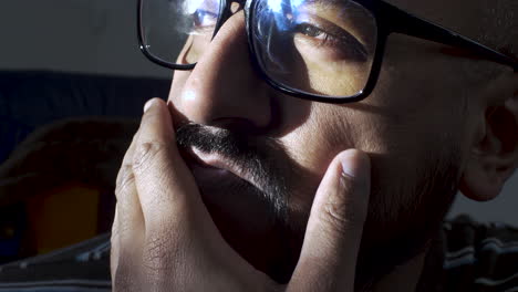 An-extreme-close-up-of-the-face-of-an-Indian-man-as-he-anxiously-fidgets-stroking-his-facial-hair,-the-man-physically-present-but-his-mind-lost-in-deep-thoughts-as-he-stares-into-the-distance