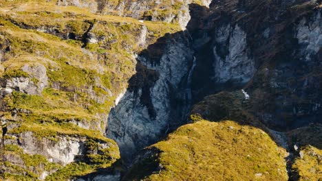 Top-down-shot-of-vegetated-moraine-rocks-of-mountains-lighting-by-sun---Rees-Valley,New-Zealand