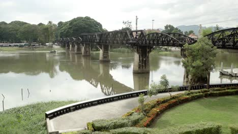 A-tilt-establishing-shot-of-the-world-war-2-iconic-bridge-over-the-River-Kwai,-Kanchanaburi,-Thailand