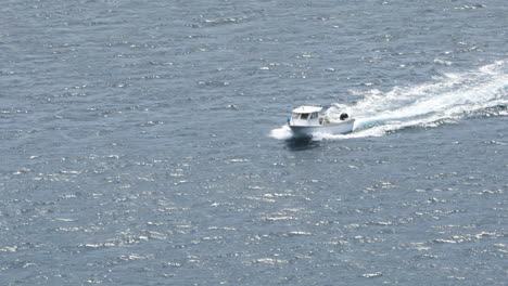 Tracking-shot-high-angle-of-motor-fishing-boat-break-waves,-Dingle,-Ireland,-day