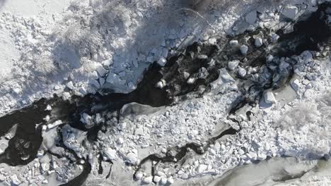 Aerial-footage-of-the-Eagle-River-with-snow-on-the-banks,-rising-slowly