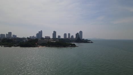 Aerial-footage-sliding-to-the-right-of-the-beachfronts-and-the-Sanctuary-of-Truth-silhouetting-with-buildings-in-the-background,-Pattaya,-Chonburi,-Thailand