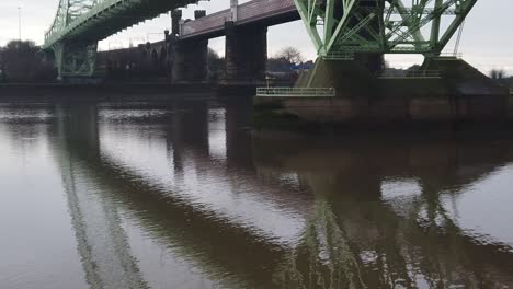 Runcorn-Silver-Jubilee-Suspension-Bridge-Reflexionen,-Die-Im-Fluss-Mersey-Unter-Der-Pfanne-Rechts-Plätschern
