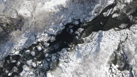 Aerial-footage-of-the-Eagle-River-with-snow-on-the-banks,-rising-and-turning