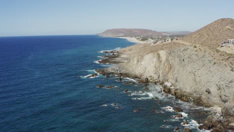 Super-Coole-Filmische-Aufnahme-Der-Klippen-In-Der-Nähe-Des-Strandes-Von-Los-Cerritos-An-Einem-Sonnigen-Tag-Mit-Den-Blauen-Wasserwellen,-Die-Die-Felsen-In-Mexiko-Brechen