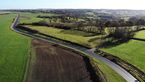 Aerial-shot-of-a-road-through-the-East-Devon-Countryside-on-a-beautiful-clear-sunny-day