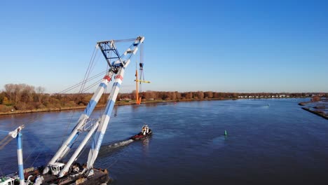 Crane-Ship-Being-Pulled-By-A-Tugboat-Across-Inland-River-In-Barendrecht,-Netherlands