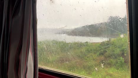 Rainy-coastal-landscape-from-inside-modern-travel-home,-static-window-view