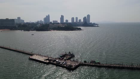 Aerial-ascending-footage-of-the-Pattaya-Fishing-Dock-and-the-Sanctuary-of-Truth-in-the-distance-with-high-rise-condominiums,-Pattaya,-Chonburi,-Thailand