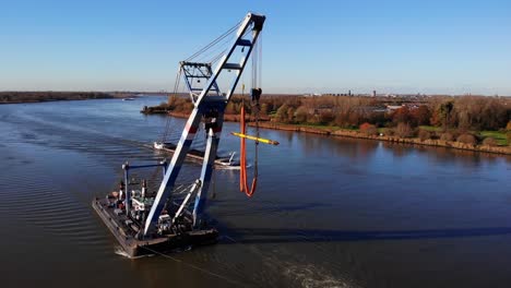 Tugboat-and-Floating-Sheerleg-Navigating-The-River-With-Vast-Riverside-Landscape-In-Barendrecht,-Netherlands
