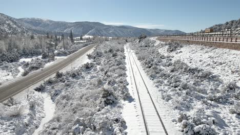 Flying-along-unused-train-tracks-with-fresh-snow-and-Interstate-70-along-the-edge-of-the-frame
