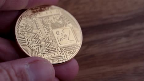 The-reverse-side-of-a-physical-Bitcoin-being-held-with-a-wooden-background