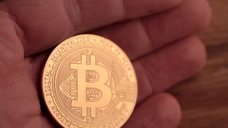 Ein-Goldener-Bitcoin,-Der-In-Einer-Hand-Ganz-Nah-Gehalten-Wird-Und-Sich-Langsam-Bewegt