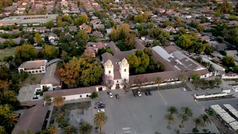 Aerial-view-of-an-orbit-over-the-San-Vicente-Ferrer-church-of-Los-Dominicos-in-Santiago-de-Chile-with-its-roof-tiles-illuminated-by-the-sun-at-sunset-with-a-residential-neighborhood---drone-shot