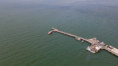Aerial-footage-revealing-the-Pattaya-Fishing-Dock-with-fishing-boats-and-vehicles-on-the-pier,-Chonburi,-Thailand