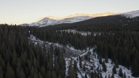 Aerial-flight-along-North-Star-Mountain-towards-a-mountain-pass-at-sunset,-with-Hoosier-Ridge-in-the-distance