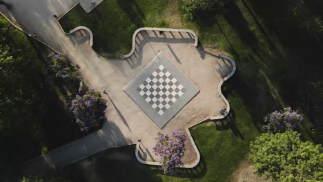 Top-view-of-a-human-scale-chessboard-with-a-person-passing-by-its-side-in-daylight---drone-shot