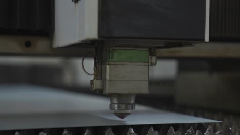 Industrial-CNC-machine-laser-moving-down-on-metal-sheet,-precision-cutter