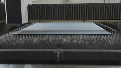 Sheet-of-metal-on-pointy-platform-moving-under-CNC-laser-cutting-machine