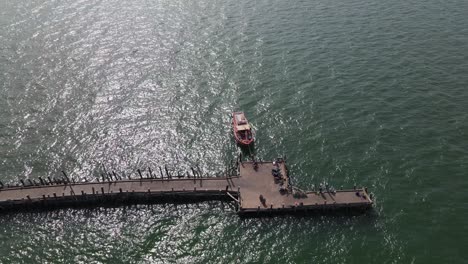 Reverse-aerial-footage-of-the-tip-of-Pattaya-Fishing-Dock-showing-a-fishing-boat-and-the-end-of-the-pier,-Pattaya,-Thailand