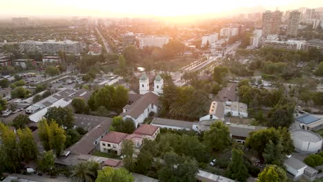 Drohnenaufnahme-Einer-Umlaufbahn-Der-Kirche-Los-Dominicos-In-Santiago-De-Chile-Mit-Dem-Sonnenuntergang-Im-Hintergrund---Luftbild