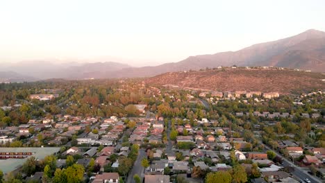 Drohnenaufnahme-Einer-Schwenkaufnahme-Von-Las-Condes-In-Santiago-De-Chile-Mit-Dem-Apoquindo-Hügel-Im-Hintergrund-Und-Bei-Sonnenuntergang---Luftaufnahme