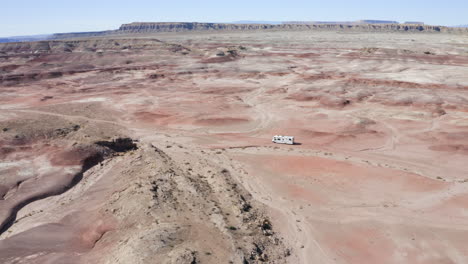 A-smooth-aerial-shot-of-an-RV-driving-through-the-Utah-desert-on-an-American-roadtrip