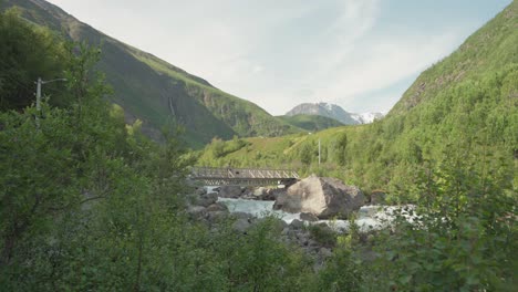 Hiker-And-Dog-Passing-Through-Bridge-In-A-Stream-At-Lyngsdalen-Valley-Norway---wide-shot