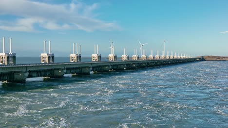Aerial-view-of-water-flowing-through-the-open-sluices-of-the-Eastern-Scheldt-storm-surge-barrier-in-Zeeland,-the-Netherlands,-on-a-beautiful-sunny-day