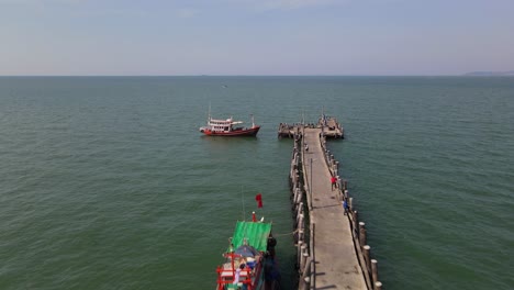 Aerial-footage-towards-the-end-of-the-Pattaya-Fishing-Dock-revealig-three-fishing-boats-and-the-pier-on-the-right,-Pattaya,-Thailand