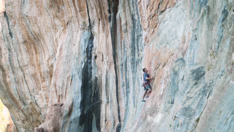 Sport-climber-ascending-a-vertical-mountain-wall
