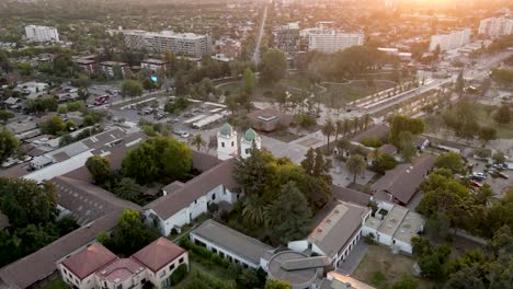 Aerial-view-of-the-church-of-Los-Dominicos-approaching-its-two-distinctive-towers-with-green-domes-at-sunset---crane-shot