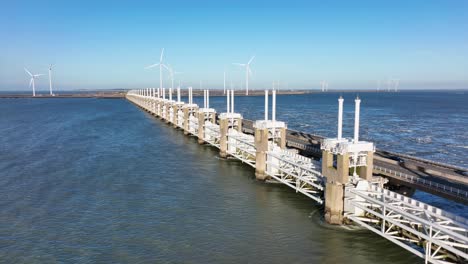 Long-aerial-shot-zooming-out-of-the-Eastern-Scheldt-storm-surge-barrier-in-Zeeland,-the-Netherlands,-on-a-beautiful-sunny-day