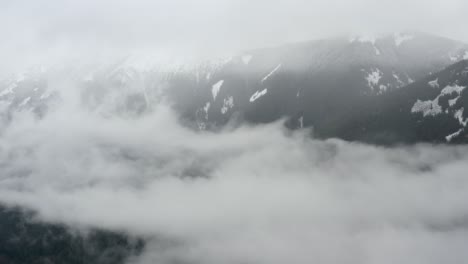 View-flying-through-clouds-toward-snow-covered-mountains