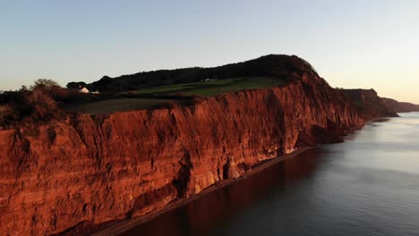 Luftaufnahme-Der-Klippen-Der-Jurassic-Coast-Bei-Sidmouth-Im-Südwesten-Englands,-Die-Von-Einem-Wunderschönen-Sonnenaufgang-Rot-Beleuchtet-Wurden