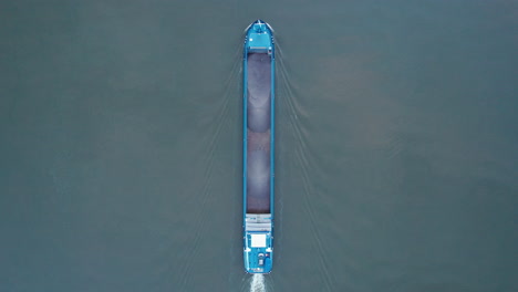 Oben-Drohnenaufnahme-Eines-Leeren-Frachtschiffs,-Das-Auf-Dem-Fluss-Amer,-Niederlande,-Flussaufwärts-Fährt
