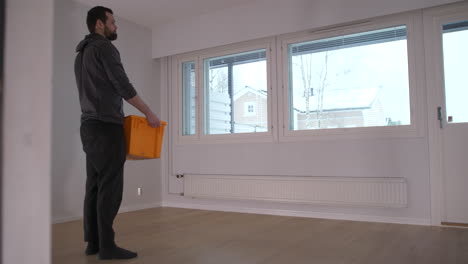 Man-about-to-move-picks-up-last-box-from-empty-room-and-walks-out