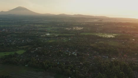 Dreamy-bright-sunrise-above-central-Bali-with-silhouette-view-of-Mount-Agung,-aerial