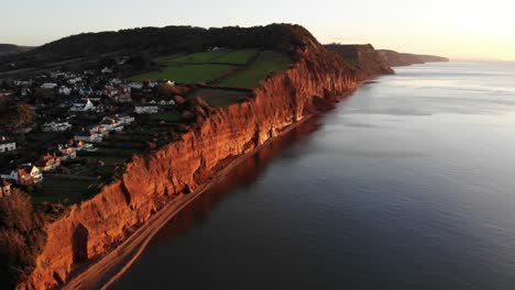Aerial-Along-Sidmouth-Coastline-Bathed-In-Golden-Sunrise-Light-In-The-Morning