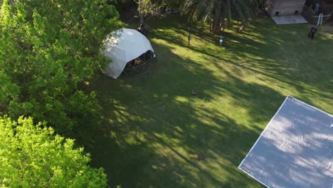 Geodesic-glamping-dome-in-garden.-Aerial-top-down-circling