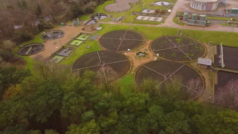Sewage-wastewater-treatment-plant-into-forest-at-Thetford,-Norfolk---aerial-timelapse-drone-circling-flight-shot