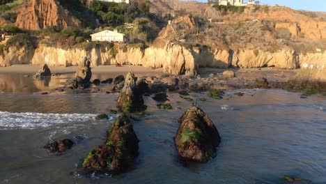 Aerial-view-of-waves-rolling-into-the-shore-at-El-Matador-Beach-during-golden-hour,-Malibu-California