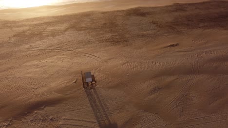 Aerial-top-down-orbiting-around-lifeguard-tower-on-beach-at-sunset,-Mar-de-las-Pampas-in-Argentina