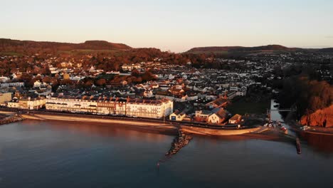 Aerial-Of-Sidmouth-Town-Esplanade-Bathed-In-Golden-Sunrise-Light