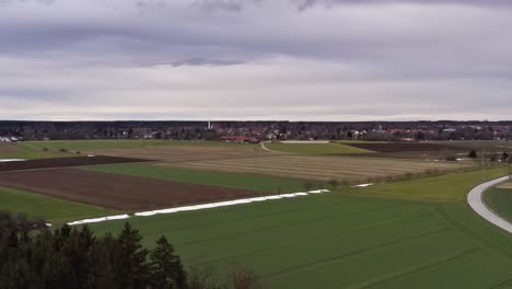 Aerial-of-a-rural-landscape-with-the-last-snow-and-a-backgrounded-town