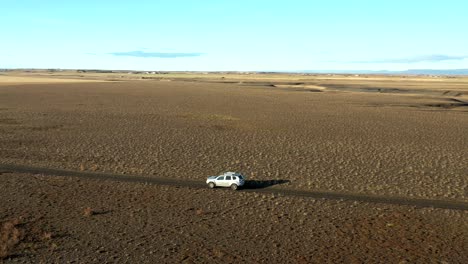 Parallax-motion-follow-offroad-vehicle-driving-on-desert-road-in-Iceland,-arid-Landscape