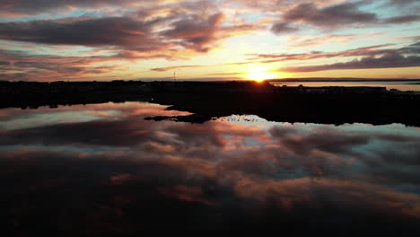 Luftaufnahme-Des-Magischen-Sonnenaufgangs-über-Der-Bucht-Und-Der-Halbinsel,-Spiegelwasserspiegelung-Des-Malerischen-Himmels