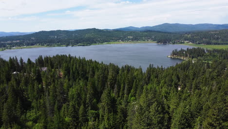 Enthüllen-Sie-Eine-Drohnenansicht-Des-Waldes-Mit-Einem-See-Im-Hintergrund-Im-Norden-Von-Idaho