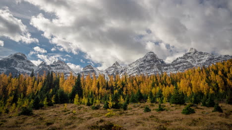 Time-lapse,-autumn-season-in-mountain-range-of-Canada,-larch-forest-valley,-snow-capped-peaks-and-clouds