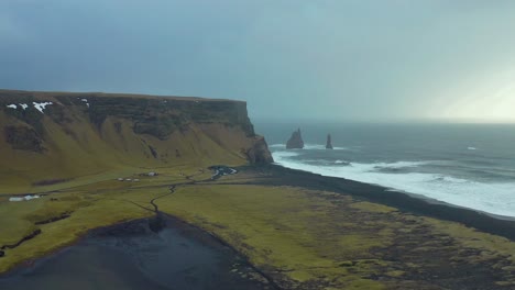 Inhospitable-thriller-landscape,-aerial-seascape-of-cliff-in-black-sand-beach,-Iceland-Halsanefshellir-panoramic